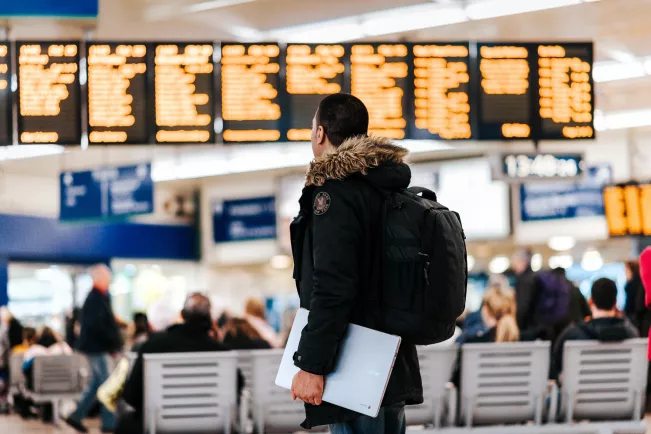 Man at the airport in front of the destinations boards_Picture by Anete Lūsiņa on Unsplash